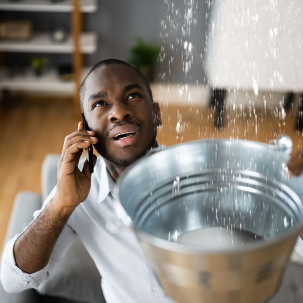 person catching water from leaking roof in bucket